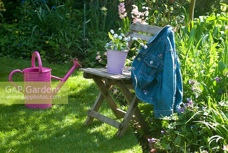 Picking Spring flowers with pink watering can in garden