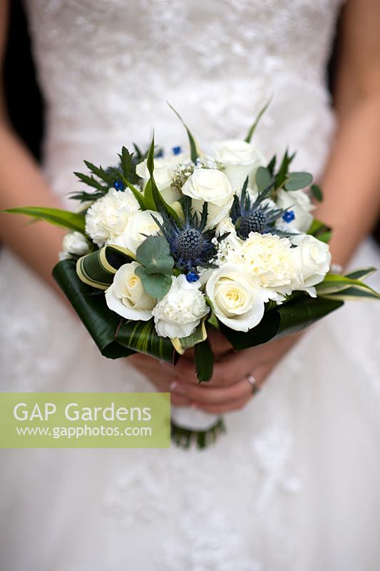 Bride holding a wedding bouquet of white  Roses, Carnation and Eryngium