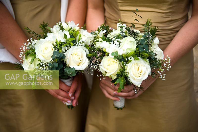 Bridesmaids holding bouquets of white roses