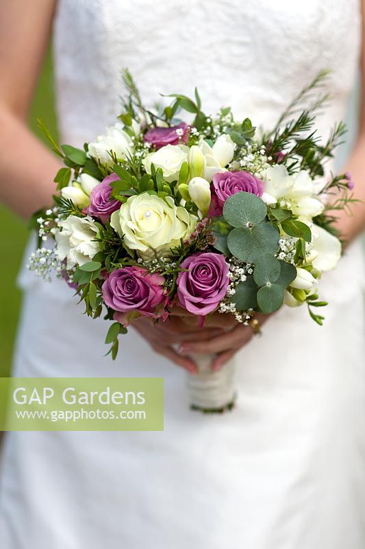 Bride holding bouquet of white and purple roses