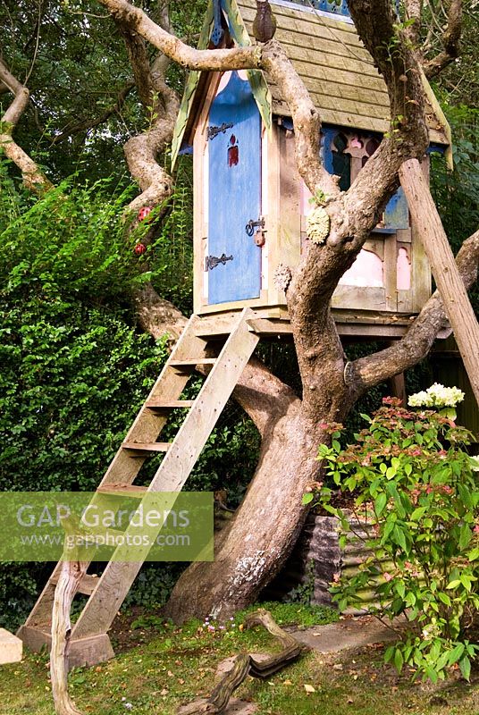 Gothic influenced tree house set amongst branches dotted with masks and birds. The Secret Garden at Serles House, Wimborne, Dorset, UK