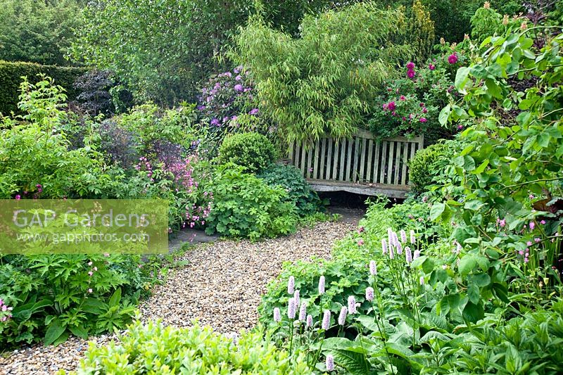 Seat and double herbaceous borders including Rosa 'Roserie de L'Hay', Persicaria bistorta 'Superba' and Silene dioca (red campion)