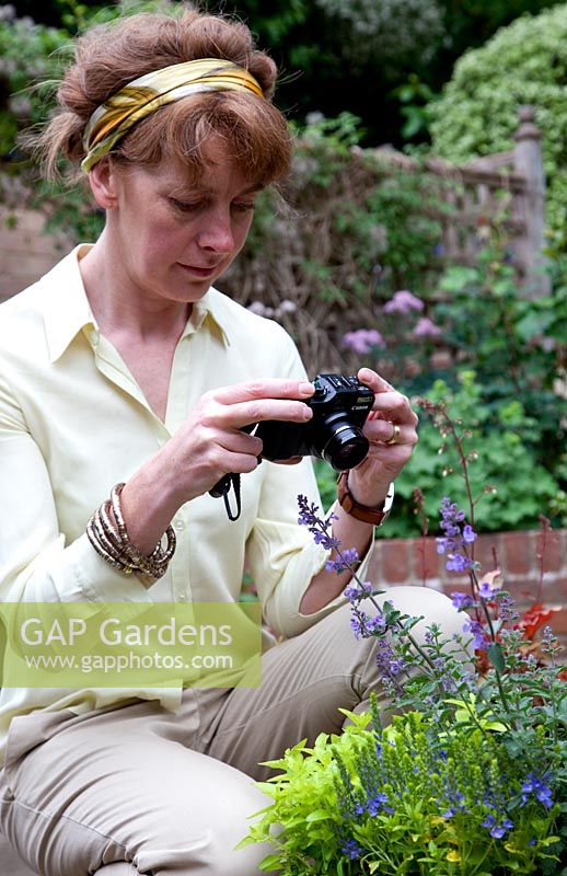 Lady in garden photographing flowers in pot