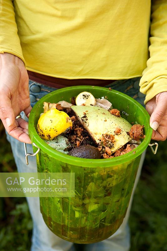 Woman holding bucket full of kitchen food waste ready for composting