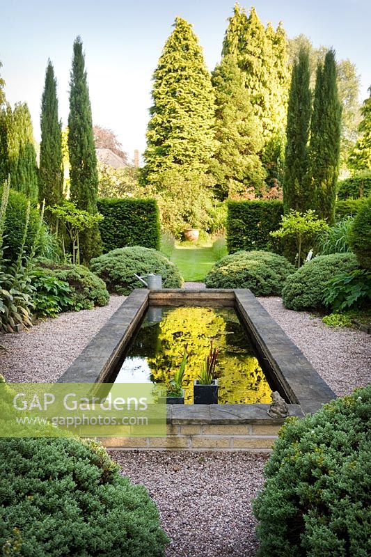 'Italian Garden' with reflecting pool and green and white planting. Structure provided by Taxus - Yew hedges, Cupressus sempervirens, Hebe sutherlandii and standard Ligustrum delavayanum - Greenways garden, Cheshire 