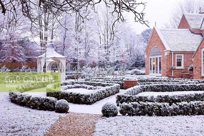 Formal town garden with gazebo and house covered in snow, Oxford, UK. 
