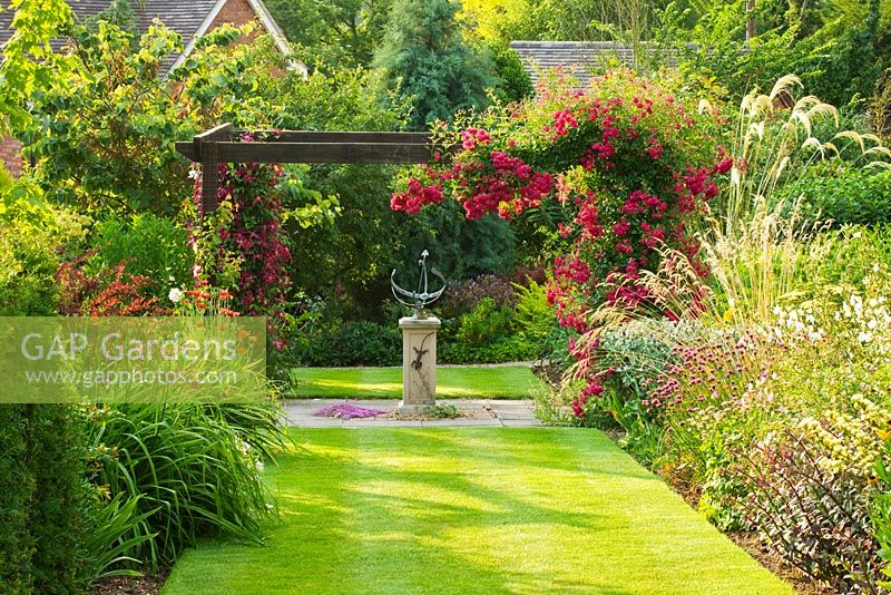 Sundial and pergola with Rosa 'Super Excelsa' - Meadow Farm, Worcestershire
