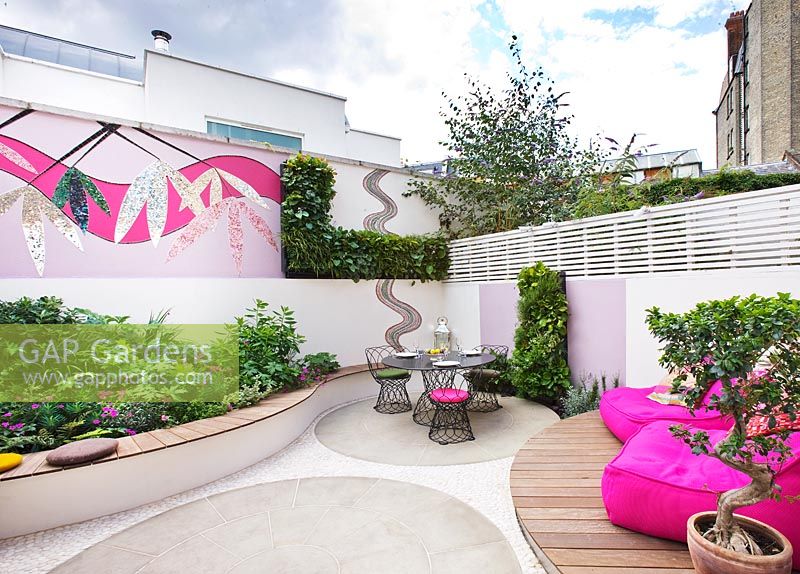 Small patio garden with decking, pink chairs, mosaic by Celia Gregory, London.
