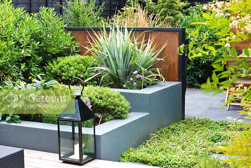 Small town garden with lantern, screens made of mild steel, and grey painted raised beds, London 
