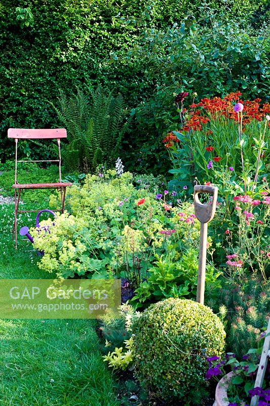 Summer border with garden fork, plants inc Alchemilla mollis, Helenium 'Moerheim Beauty' and Achillea 'Rose Madder