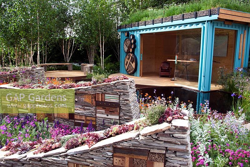 Sculptural dry stone walls with built-in insect hotels and planted with Sempervivums - Houseleeks in front of turquoise summerhouse - 'The Royal Bank of Canada with the RBC New Wild Garden' - Silver Gilt Medal Winner, RHS Chelsea Flower Show 2011