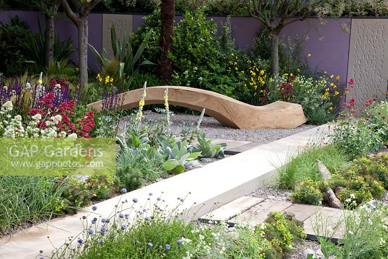 Seating area with curved timber bench and salt tolerant planting including Armeria - Thrift, and Centranthus ruber - The Cancer Research UK Garden, Silver Gilt Medal Winner, RHS Chelsea Flower Show 2011 