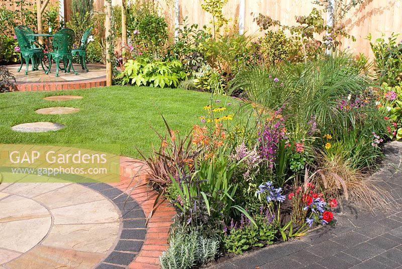 Small back garden with colourful borders, circular patios with seating and lawn with stepping stones by Mook Garden Design - Southport Flower Show 2011