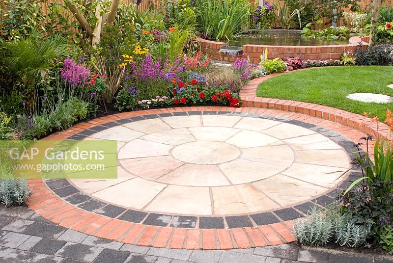 Small back garden with colourful borders, circular patio and raised brick pool by Mook Garden Design - Southport Flower Show 2011