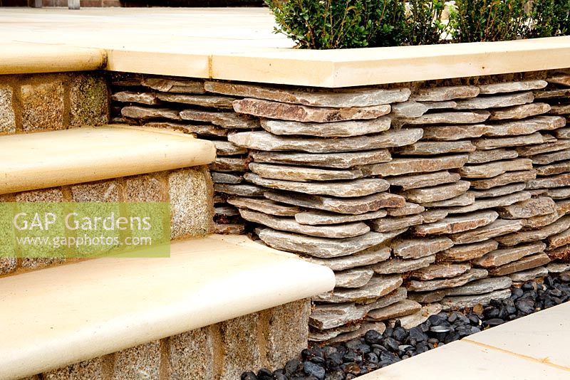 Sandstone steps and paving next to low dry stone wall

