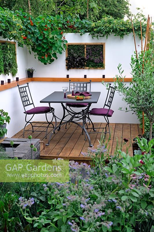 Alfresco dining area in a contemporary small garden, with scented herbs planted in vertical wall boxes.