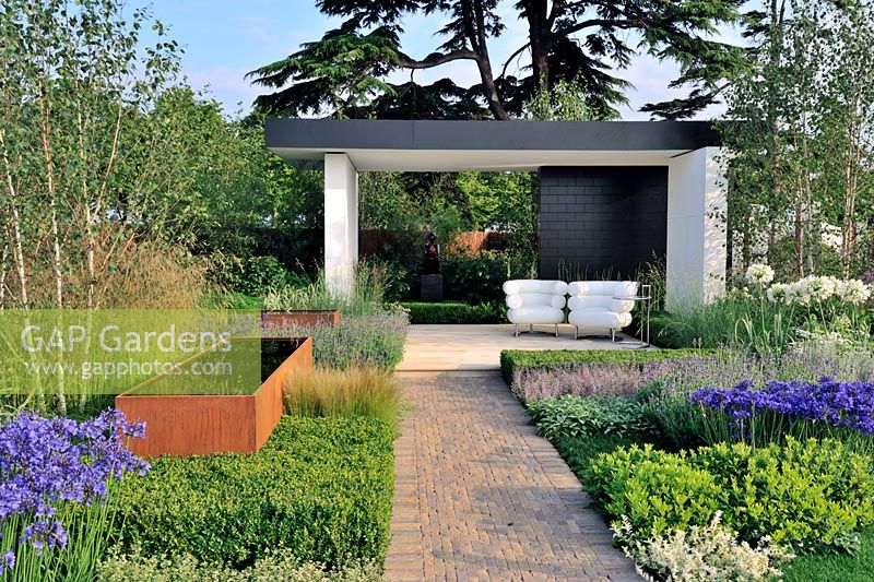 Modernist planting set in blocks with rusting water troughs around an open plan pavilion with lacquered wall