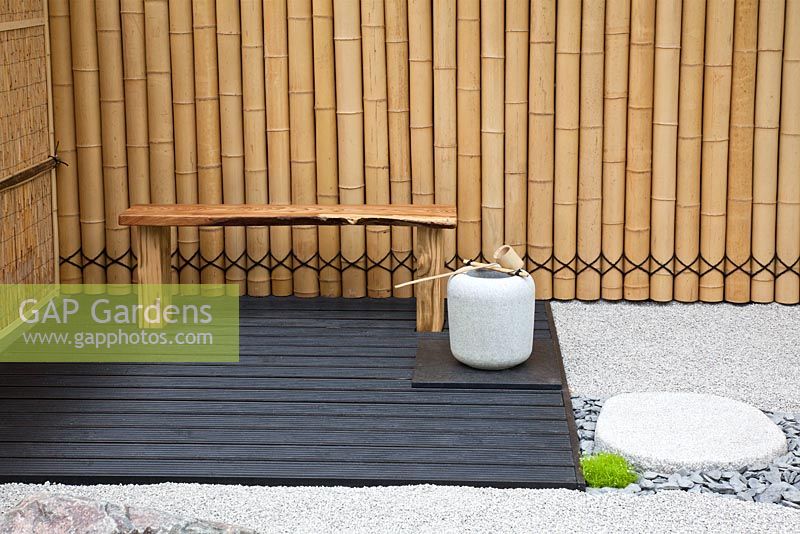 Seating area, bamboo fence and granite stones and gravel path in a Japanese themed garden  - 'Less and More' garden - RHS Hampton Court Flower Show 2011
 