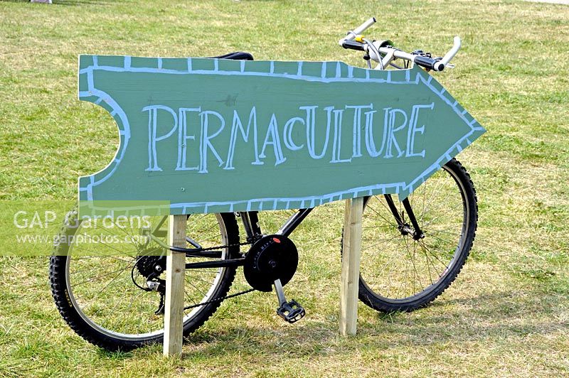 Permaculture direction sign with bicycle behind, Camden Green Fair, London UK
