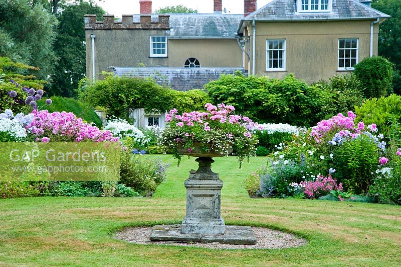 The Sickle Beds, in the formal garden to the west of the house, with central urn and beds full of Phlox, Lythrums, Crinums and other herbaceous perennials - Old Rectory, Pulham, Dorset
