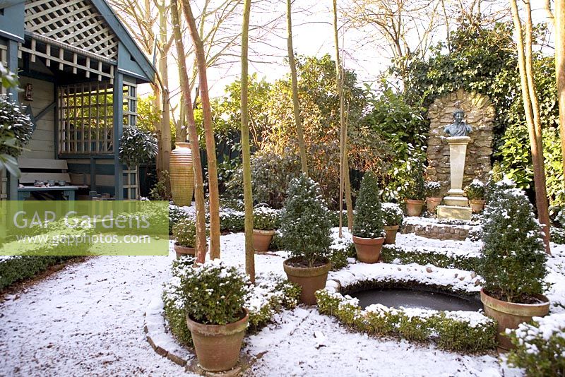 Formal garden with summerhouse, circular pond and evergreens in terracotta pots - The Old School House, Great Bentley, Essex in January