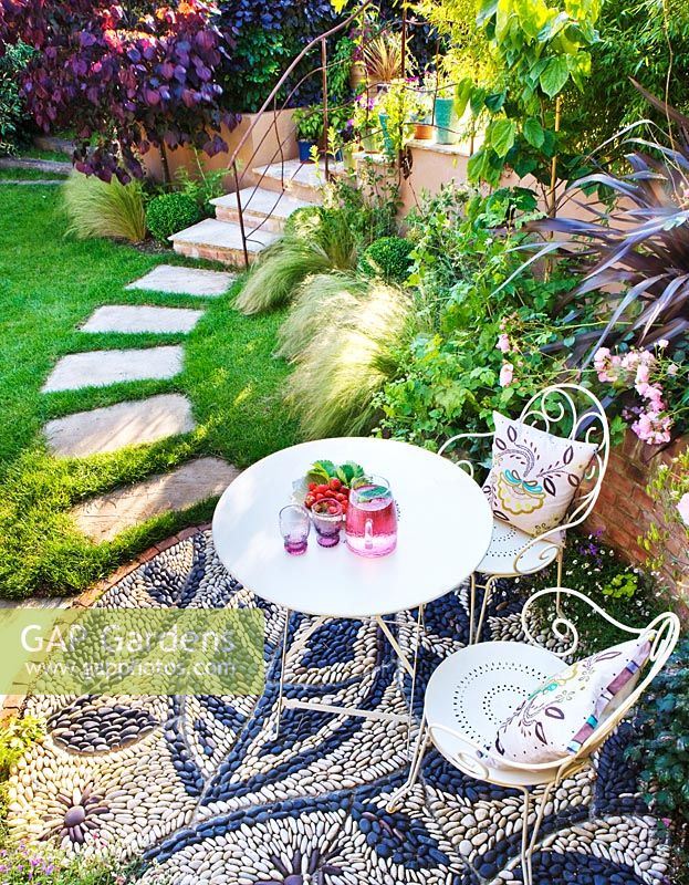Elevated view of patio with pebble mosaic, table and chairs, stepping stones leading to staircase