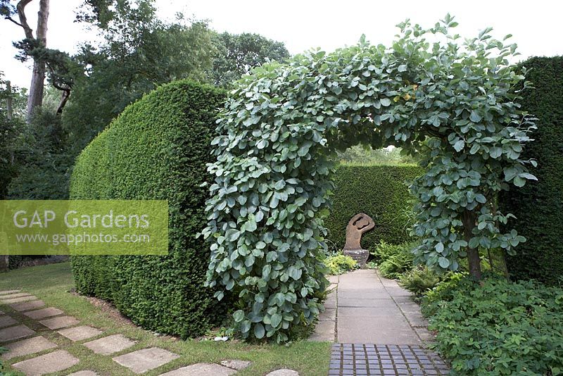 Arch with view of Simon Verity's statue 'Seated Lady' surrounded by yew hedging.