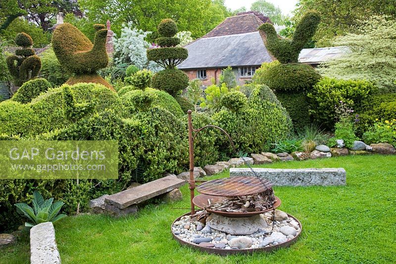 Topiary garden including Yew birds, wedding-cake tiers and crowns. Firepit atop large flint stone with kindling 