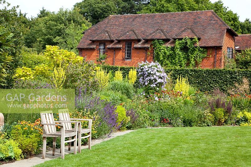 Wooden chairs in front of Summer border