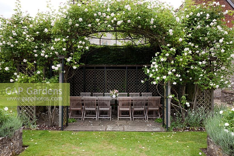 Wooden furniture in gazebo with climbing Rosa - The Flint House 
