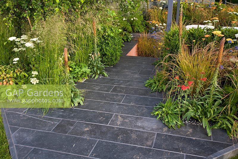 Slate patio area softened with grass borders - 'The Landform Garden' - Gold medal winner and Best Summer Garden - RHS Hampton Court Flower Show 2012 