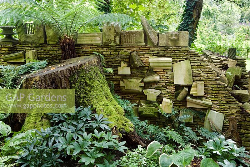 The 'Wall of Gifts' in the Stumpery consisting of various pieces of architectural stone, some of which were given to HRH The King, others he has collected. The Stumpery is based on a Victorian concept of growing ferns amongst tree stumps. Highgrove Garden, August, 2007. 