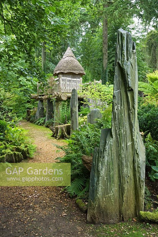 The thatched tree house 'Hollyrood House' in the Stumpery has a rustic platform made of oak and is supported by shards of Welsh slate. Highgrove Garden, August 2007. 