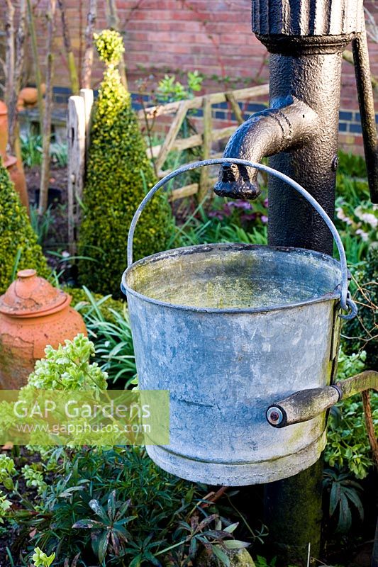 Decorative water pump and bucket in spring vegetable garden