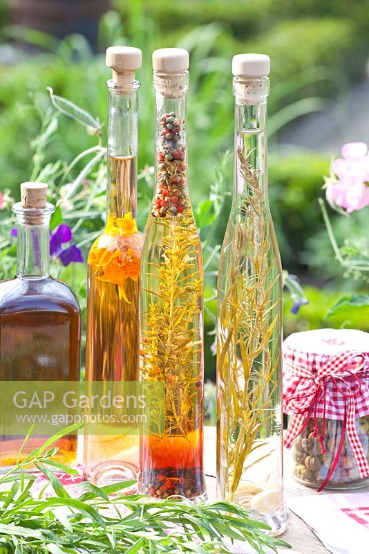Herbal, tarragon and nasturtium vinegar on garden table 