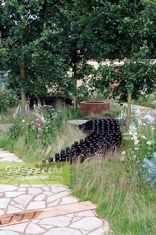Rows of empty beer bottles snaking through wild flower garden. The badger beer garden, Hampton Court flower show 2012