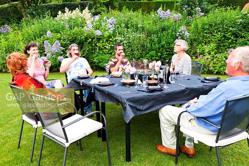 Socialising with friends around table on the lawn by the Crescent Border - Veddw House Garden, Monmouthshire, Wales