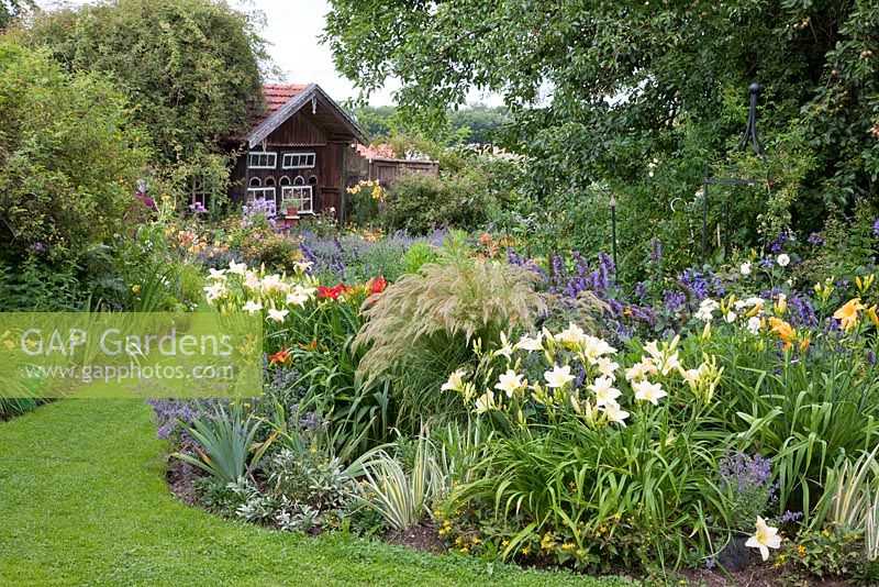 Bavarian country garden in July - perennial borders and a bee house 
