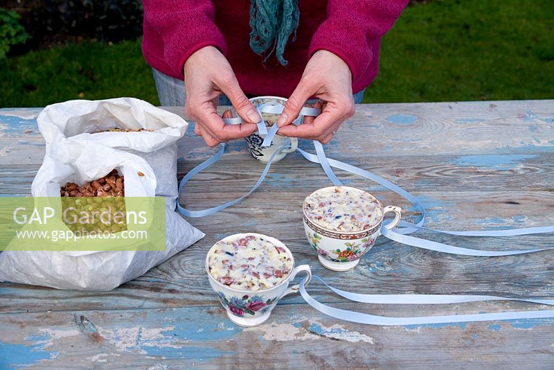 Step by step for creating hanging birdfeeders out of teacups and yoghurt pots - tying ribbon to cups to suspend 