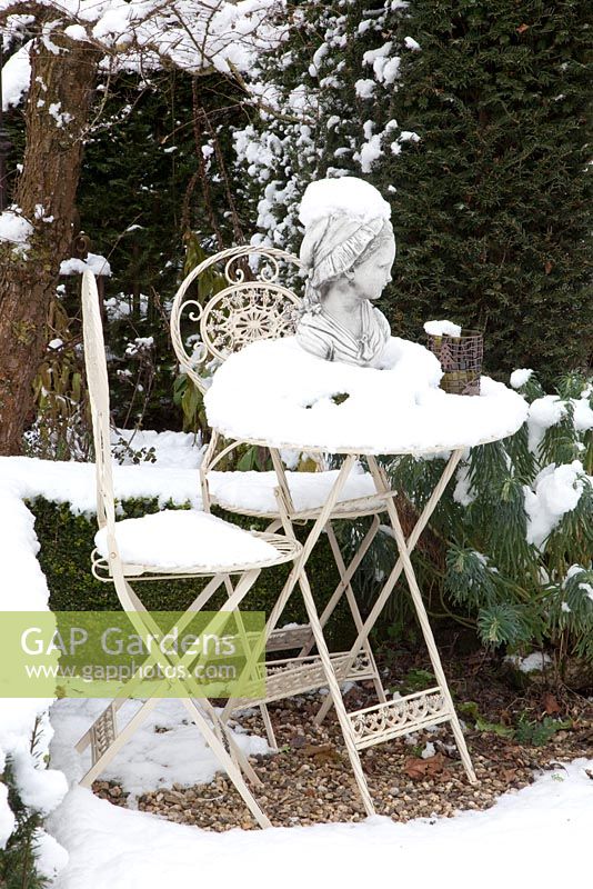 Statue on table covered in snow with Taxus and Euphorbia planting