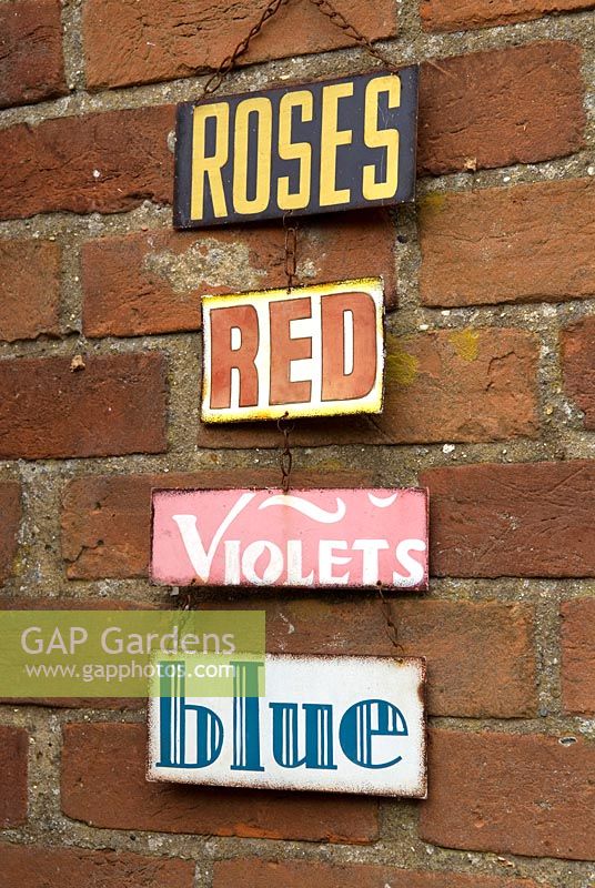 Decorative garden signs hanging on brick wall