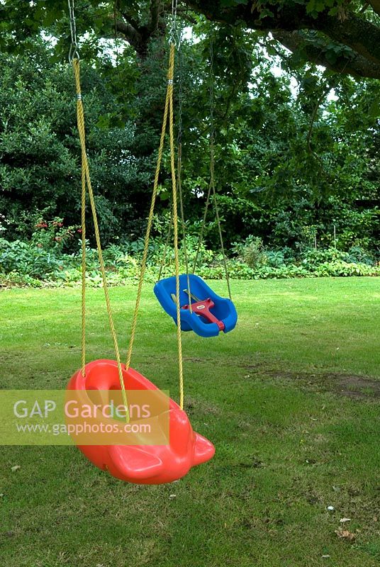 Childrens' novelty swing seats, suspended from bough of tree - Furze House NGS, Rushall, Norfolk