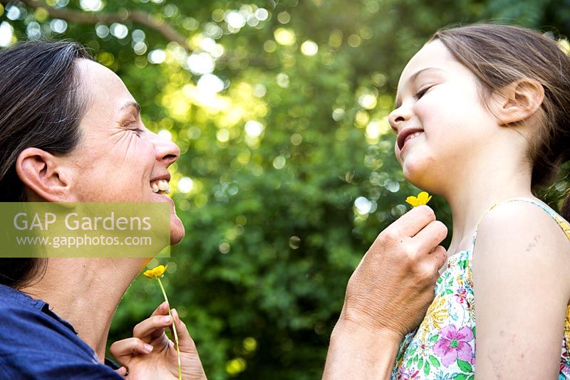 Mother and daughter playing with Ranunculus repens - Creeping Buttercup