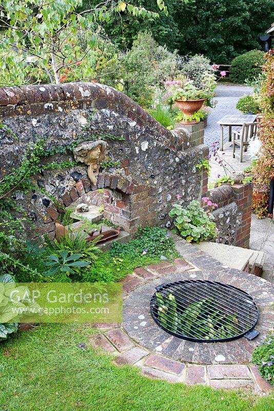 Flint wall and old well as decorative feature - NGS garden Oxsetton