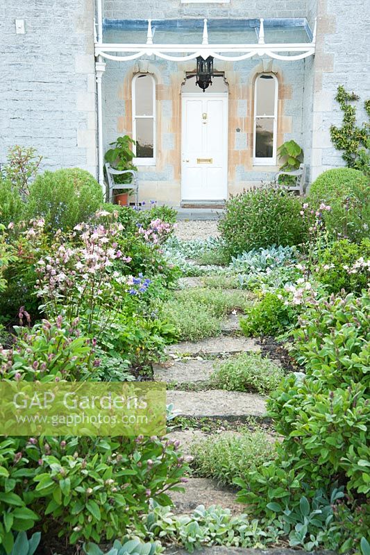Circular bed in front of the house is planted with herbs including sage and rosemary, plus silvery Stachys byzantina 'Silver Carpet' and self seeded aquilegias. Westbrook House, West Bradley, Somerset, UK