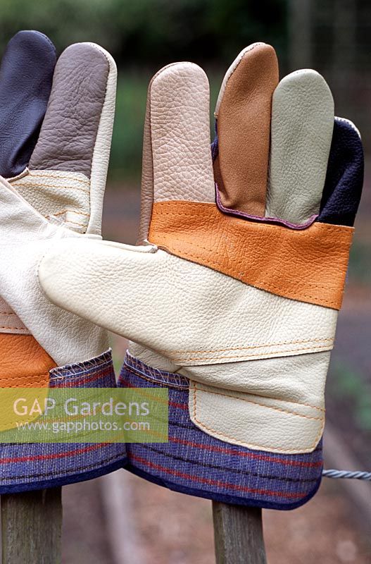 A new pair of patchwork gardening gloves on a fence