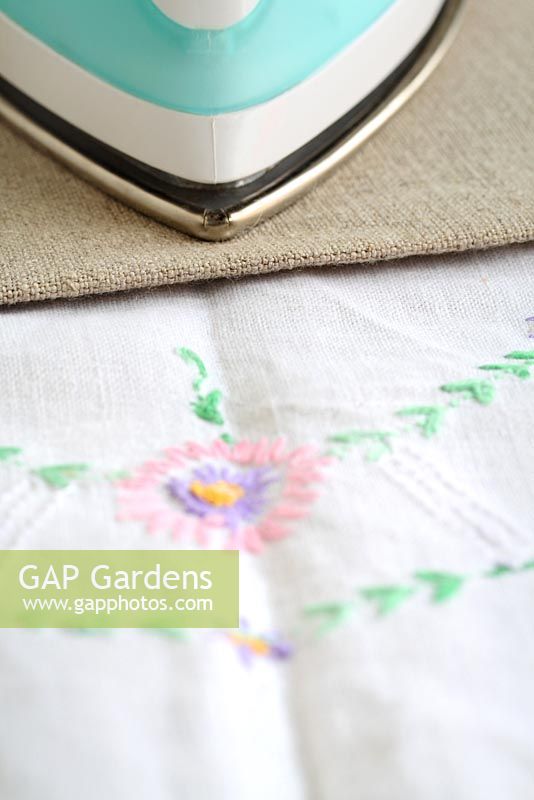 Step by step of making garden bunting with vintage linens and buttons - Using a cloth on top of the delicate embroidered linens, iron out any creases