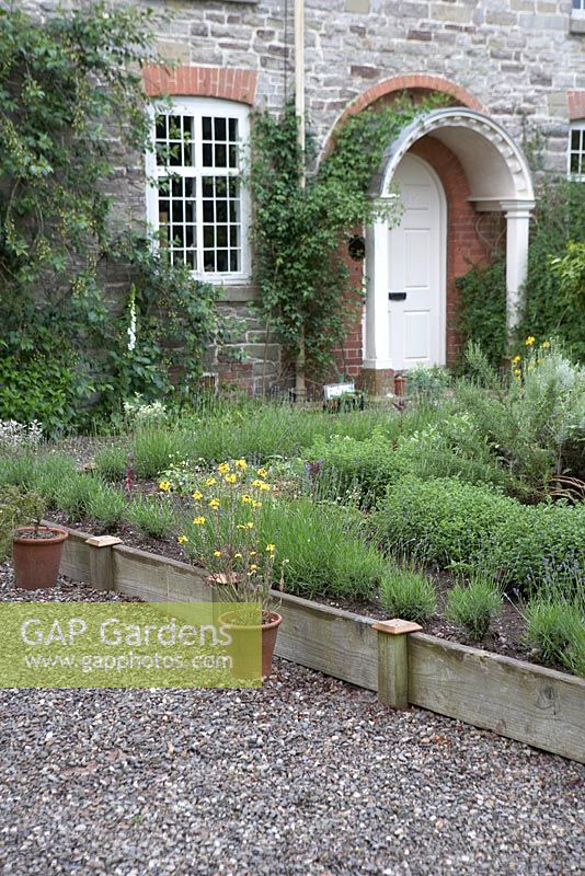 The Dower House Garden at Morville showing The Knot Garden outside the house. Herbs including marjoram, thyme, sage and wild strawberry surrounded by gravel.