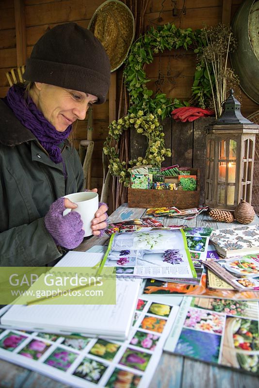 Woman sat in shed garden planning during Winter, for the following year to come.