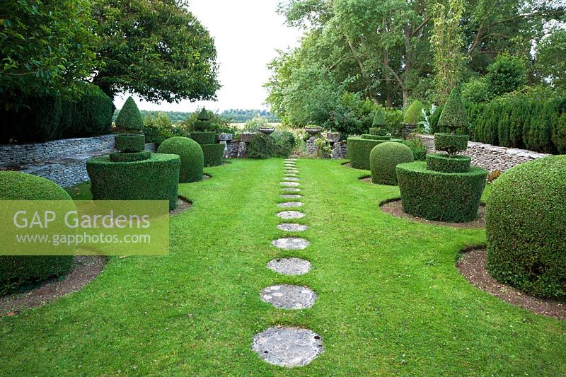 Topiary garden features clipped box shapes either side of a lawn with circular stepping stones leading southwards to the White Borders